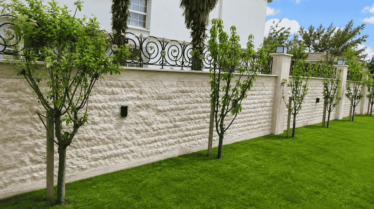Muro externo com revestimento Rockface Travertino em área ajardinada